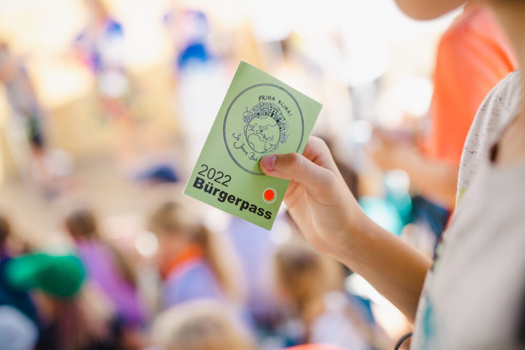 Ein Spielkind hält einen Bürgerpass der Spielwoche in der Hand.