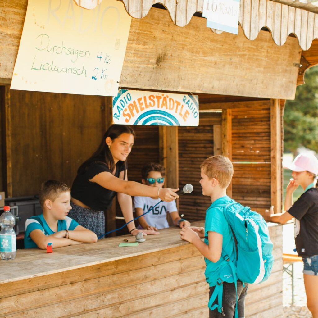 Ein Spielkind spricht live ins Mikrofon in der Arbeitsstelle Radio der Spielstadt Bad Kresselnau.