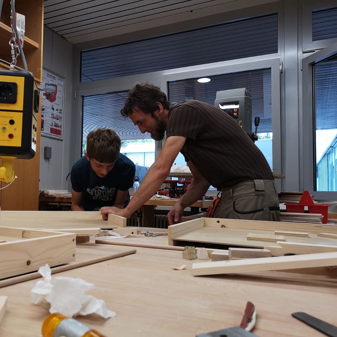 Ein Spielkind arbeitet gemeinsam mit einem Betreuer in der Arbeitsstelle Schreinerei der Spielstadt Bad Kresselnau.