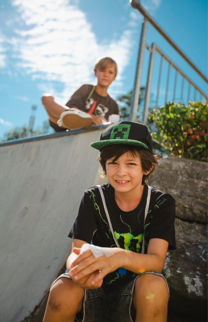 Zwei Spielkinder der Spielstadt Bad Kresselnau sitzen entspannt im Außenbereich des Geländes.